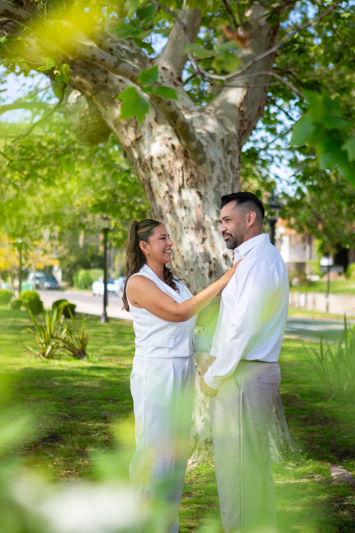 La pareja sonriendo junto a un árbol
